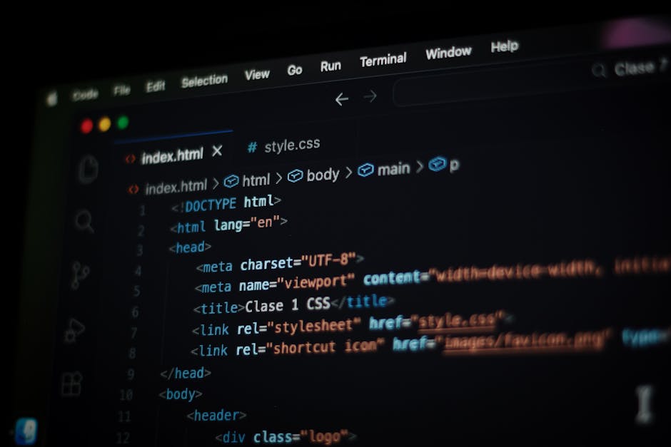 Close-up of a person's hand using a laptop with an open code editor on the screen, featuring lines of programming code in various colors on a dark background. The laptop is positioned on a wooden surf
